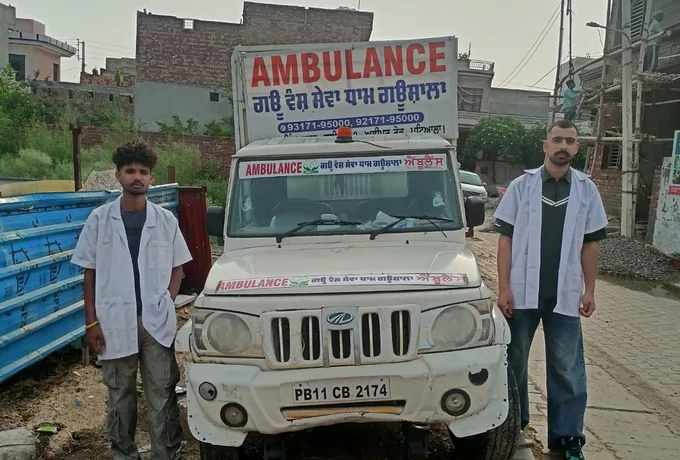 The gaushala's own ambulance truck with two staff in white coats standing beside it, ready for a rescue call.